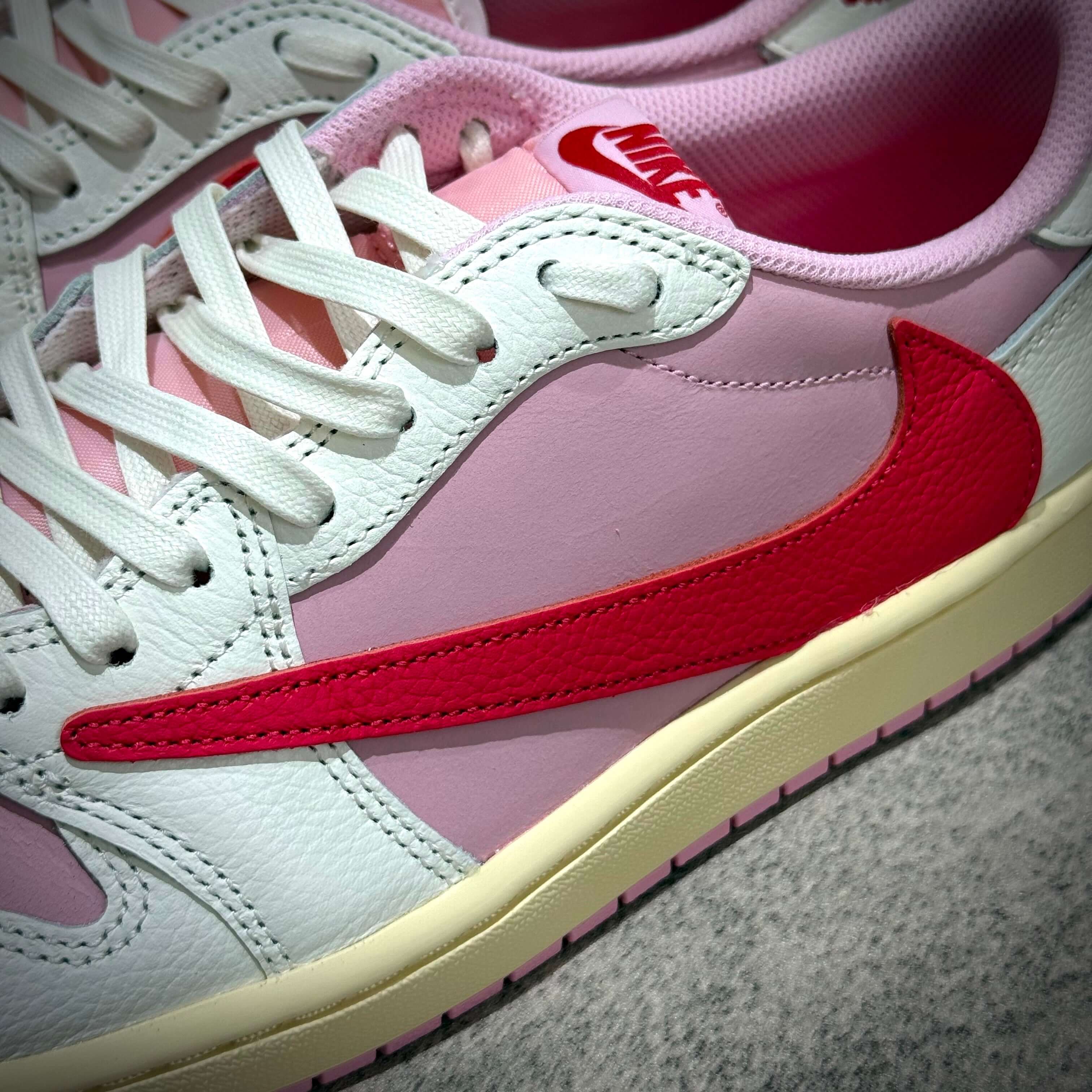 Travis Scott × Nike Air Jordan 1 Retro Low SP Tropical Pink sneakers featuring pink and red colorway with prominent Nike Swoosh.
