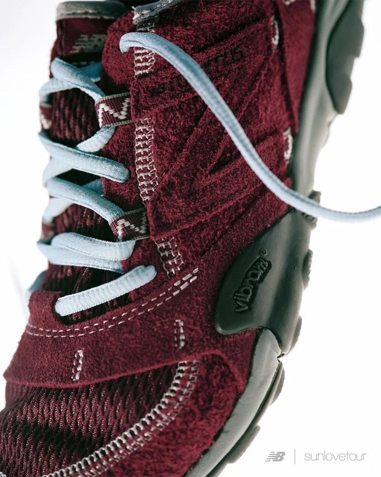 Close-up of SUNLOVETOUR x New Blance MT1001ND shoe showcasing burgundy color and light blue laces.