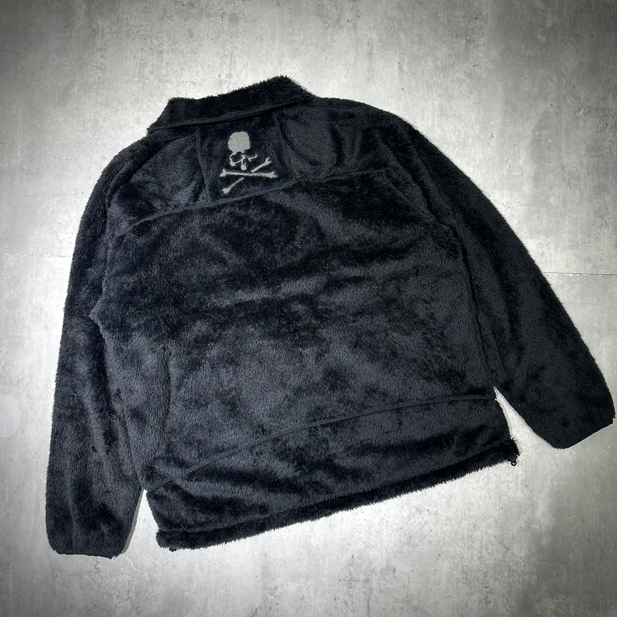 Wild Things x Mastermind World Shaggy Zip Up Jacket featuring a cozy black fur design with skull logo on the back.