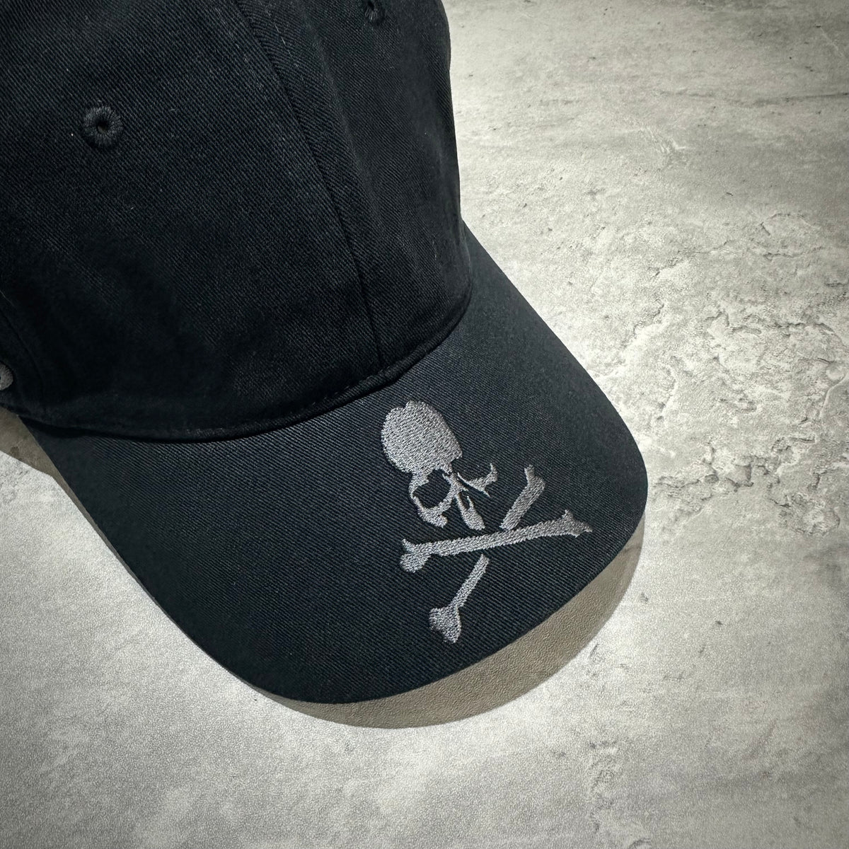 Wild Things x Mastermind World Tee Cap featuring a stylish black design with skull and crossbones emblem on the front.
