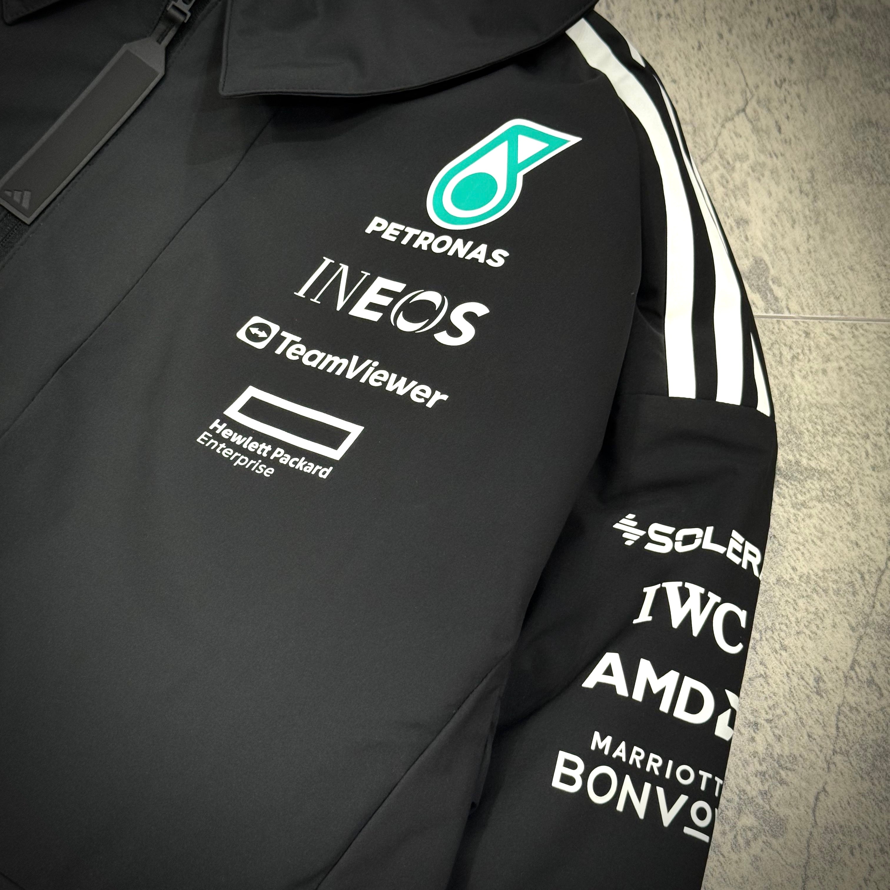Detail view of Adidas x Mercedes AMG Petronas 2025 F1 Team Jacket JX0748 showcasing team sponsor logos.