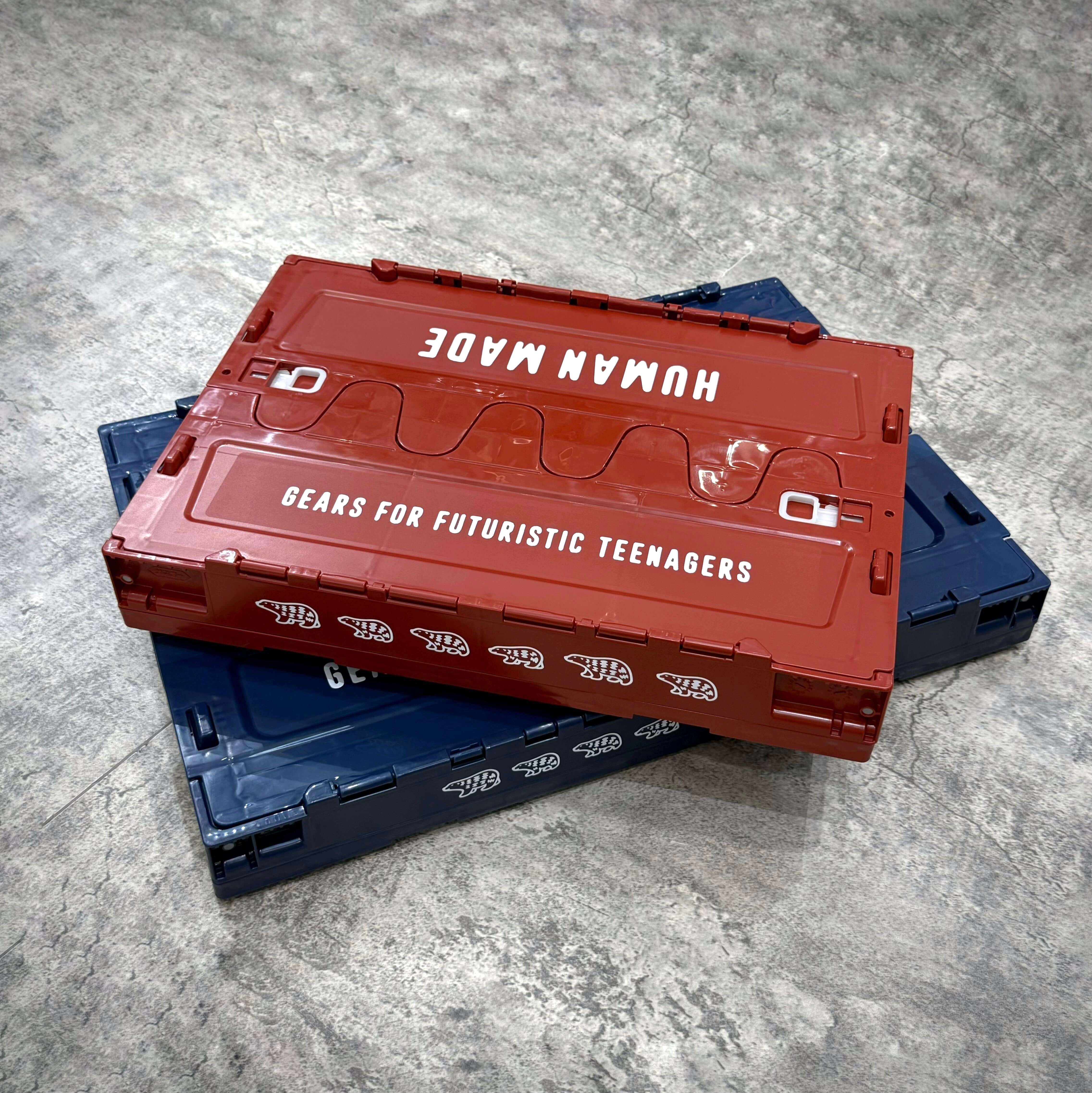 Human Made Container in red and blue stacked on a textured surface with branding visible.