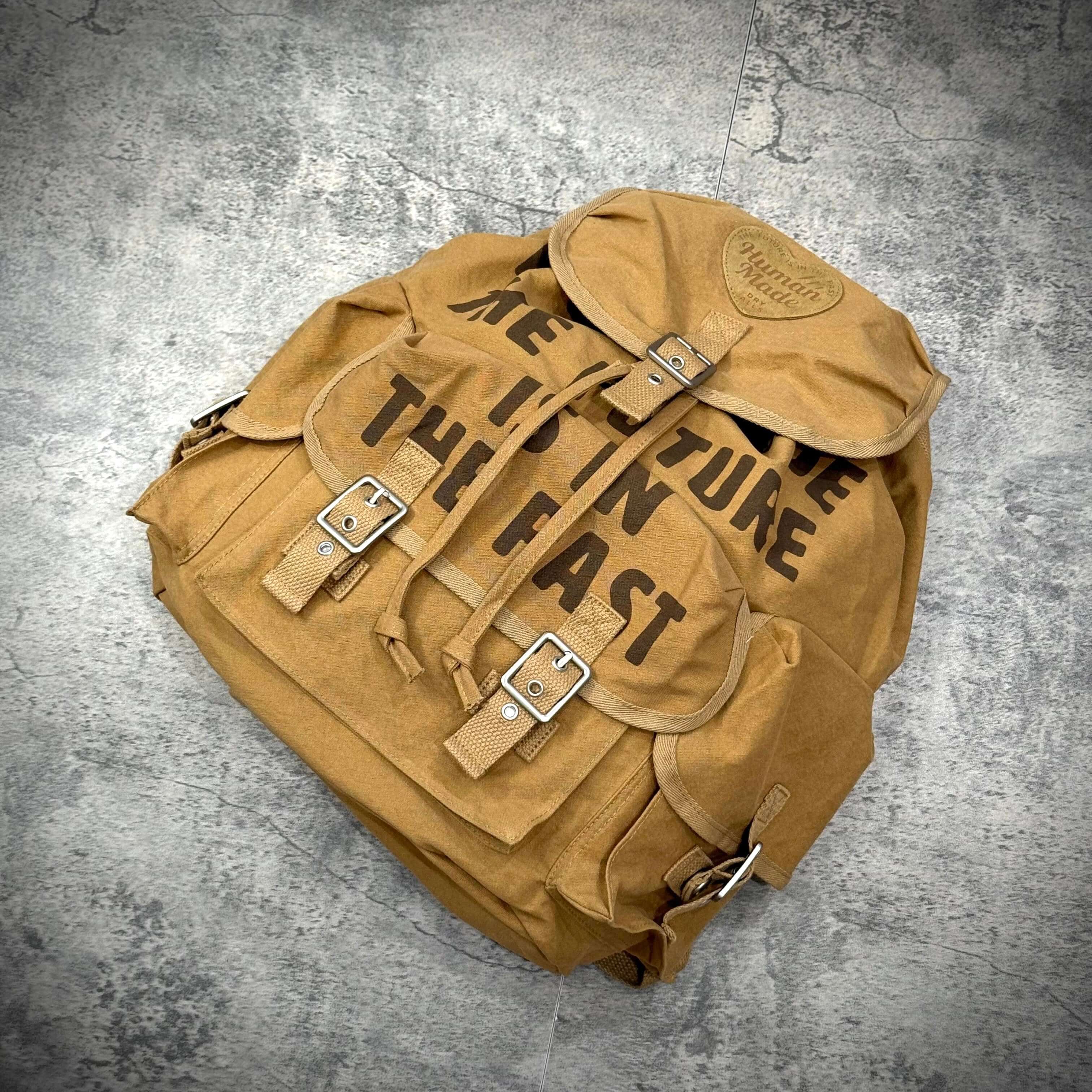 Human Made Hunting Backpack displayed on a gray surface showcasing its unique design and durability.